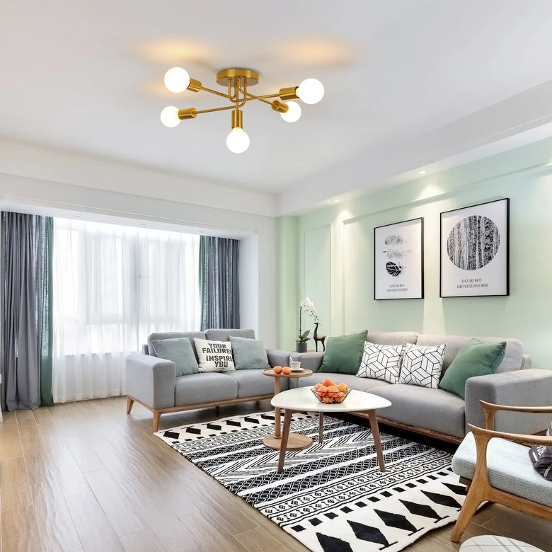 Modern living room featuring Gold 5-Light Sputnik Ceiling Light with glowing white globe bulbs, styled with a gray sectional sofa, black-and-white patterned rug, and light green walls.