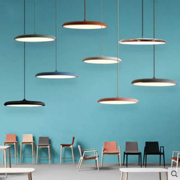Minimalist Metal Hanging Lamp in various colors suspended in a modern space with stylish chairs.