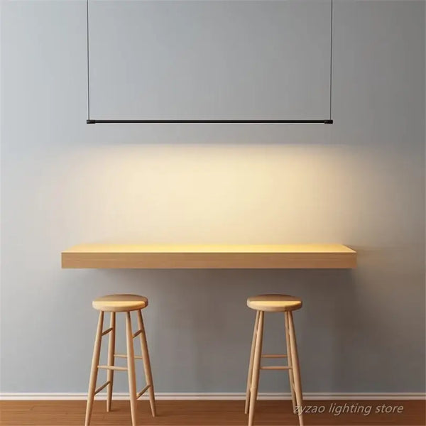 Super Simple Line Lighting | Modern LED Pendant Lamp illuminating a minimalistic table and stools in a contemporary setting.