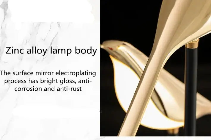 A close-up product photo of a modern sculptural lamp body made of shiny gold-toned zinc alloy, shown against a black background with a small inset detail view and text describing the zinc alloy finish.