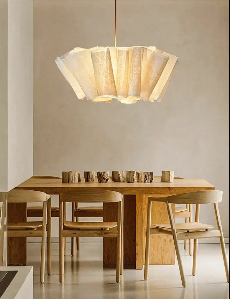 Fabric pleated Chandelier hanging above a modern wooden dining table with chairs, enhancing the space.