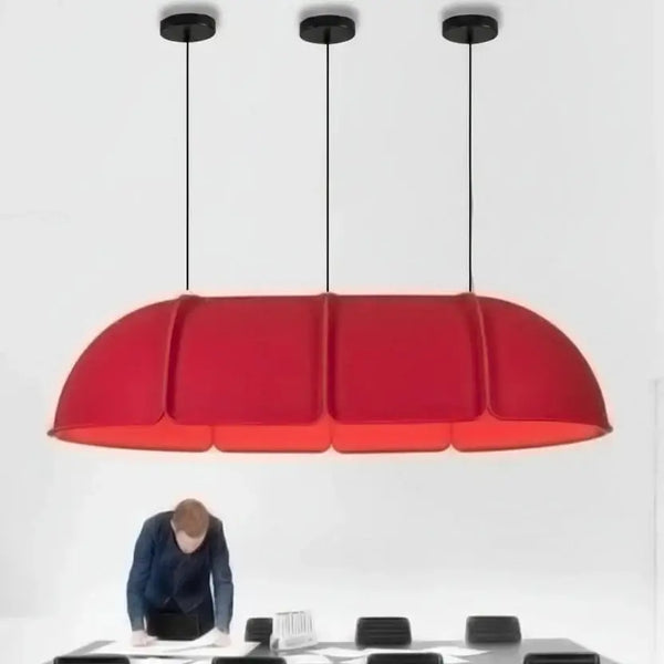 hero A modern red dome-shaped pendant light hanging above a black dining table and chairs in a minimalist room, with a person standing at the table below.