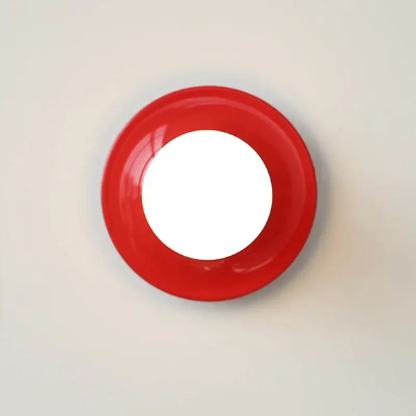 80s revival wall light in UFO shape with vibrant red color and circular design on plain wall.