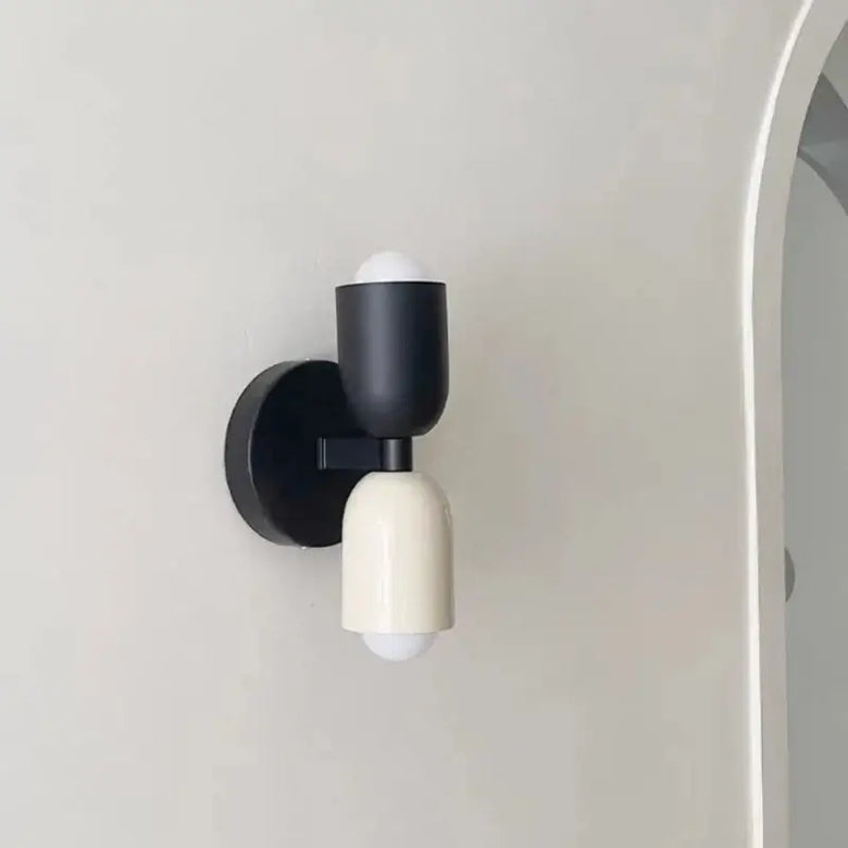 Modern wall light fixture with black and white design on a neutral background