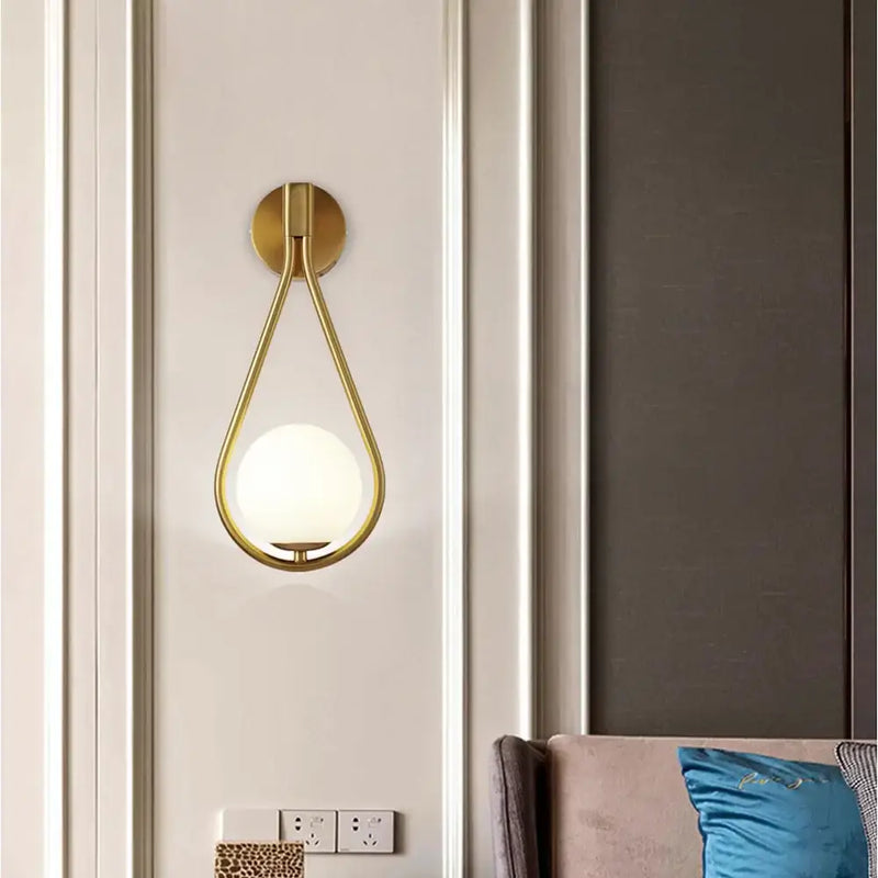 Drop Luxury Glass Ball Wall lamp in gold finish illuminating a contemporary living space.