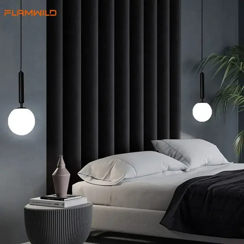 Mid-Century Modern Glass Ball Pendant Light hanging above a stylish bed in a contemporary bedroom setting.