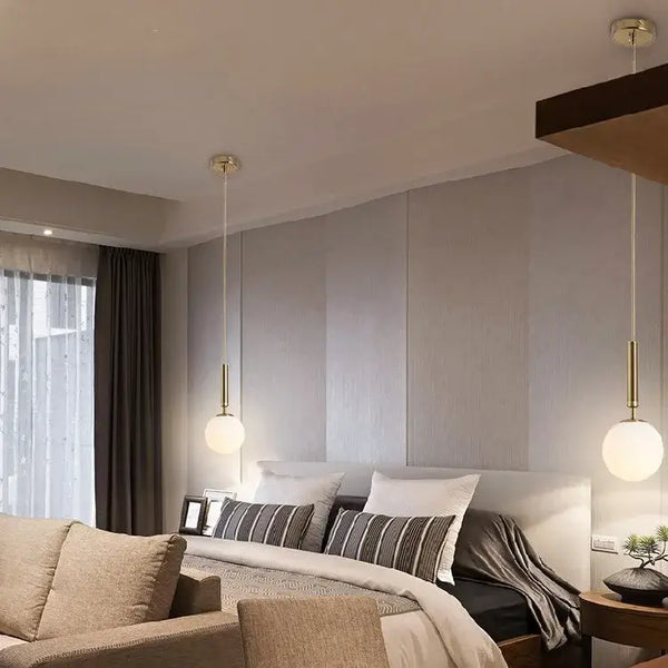 Modern Gold Glass Ball Pendant hanging over a stylish bedroom, illuminating the space with elegance.