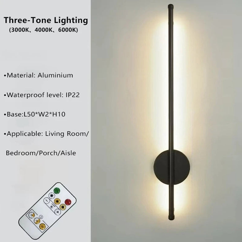 Three-tone wall sconce light fixture with a slim vertical aluminum pole, round backplate, and warm white LED illumination, shown beside product text and a small remote control on a light gray background.