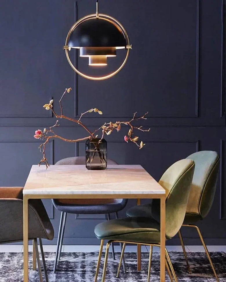 Dining area with a wooden table, green chairs, and a modern pendant light against a dark paneled wall.