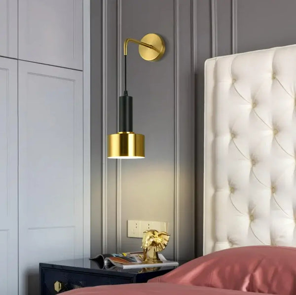 Gold Wall Mounted Spot in Brass and Black Colours lighting elegantly positioned beside a plush bed in a modern bedroom.