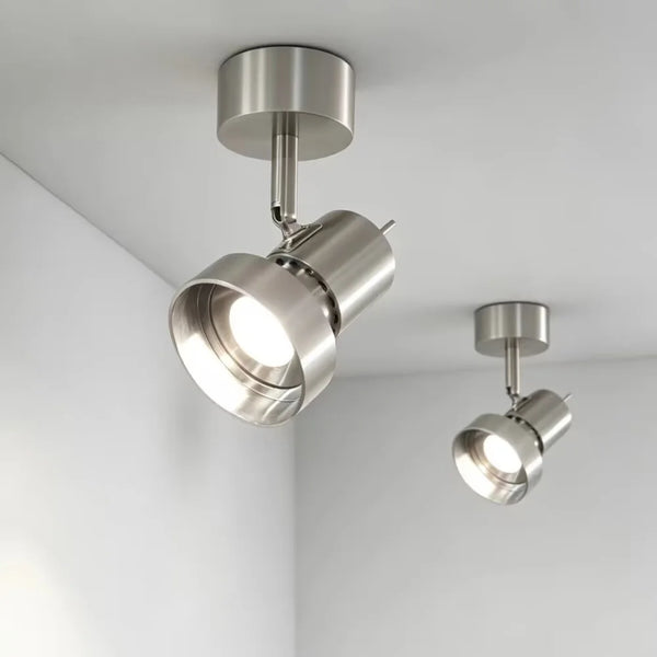 Two modern ceiling-mounted track spotlight lights in brushed silver metal, shown installed on a white ceiling in a room corner.