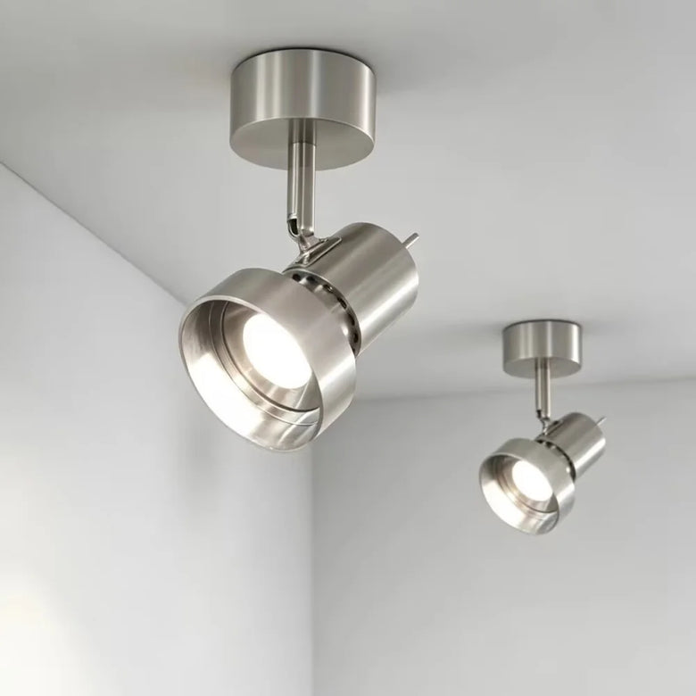 Two modern ceiling-mounted track spotlight lights in brushed silver metal, shown installed on a white ceiling in a room corner.