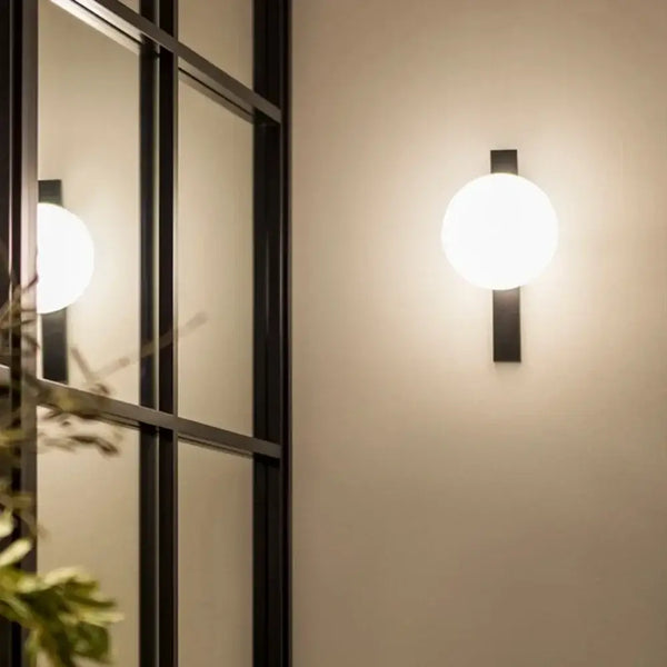 Decorative Lighting Fixture With Milk White Glass Sphere mounted on wall reflecting light.