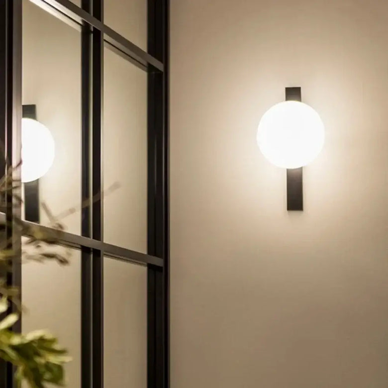 Decorative Lighting Fixture With Milk White Glass Sphere mounted on wall reflecting light.