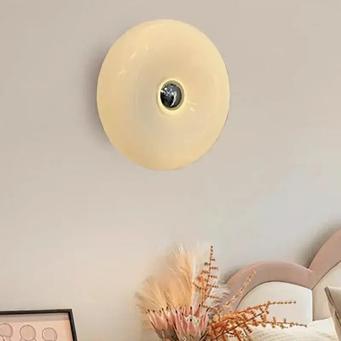 Glass Donut Wall Lamp elegantly illuminating a modern living space with cream glass shade.
