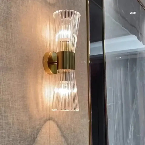 Unique Collection of Art Deco Sconces featuring elegant clear glass and gold accents on a textured wall.