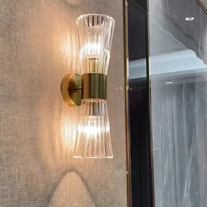Unique Collection of Art Deco Sconces featuring elegant clear glass and gold accents on a textured wall.