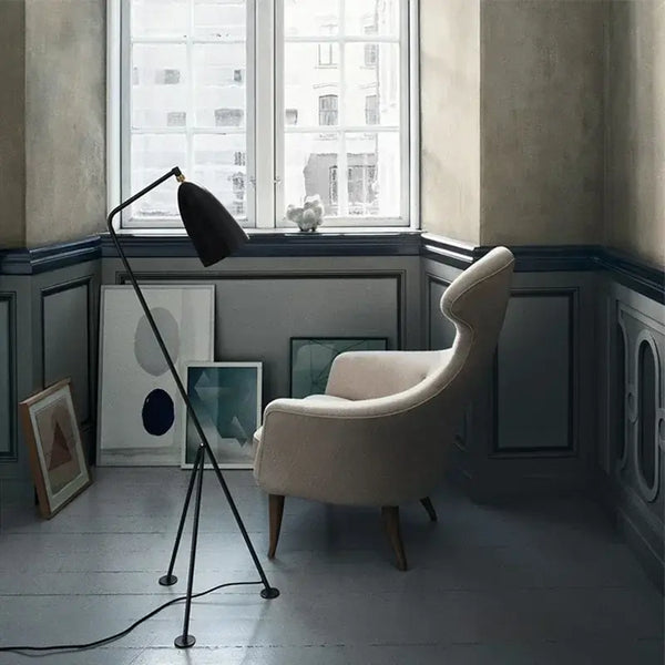 Danish Designer Grasshopper Floor Lamps illuminating a cozy corner with a stylish chair and art on the walls.