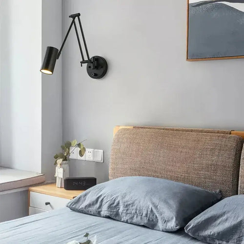 Vintage Loft Bedside Reading Light Fixture on a wall beside a cozy bed with gray linens.