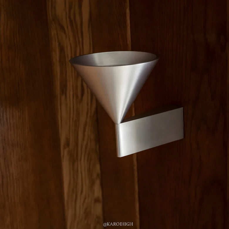 Metallic funnel-shaped object attached to a wooden surface