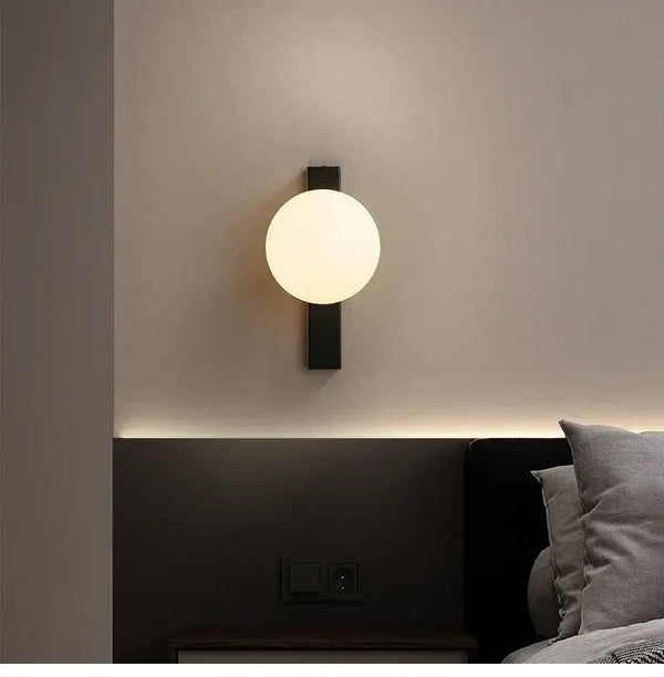 Minimalist Nordic Wall Lamp with Frosted White Ball illuminated on a modern bedroom wall.