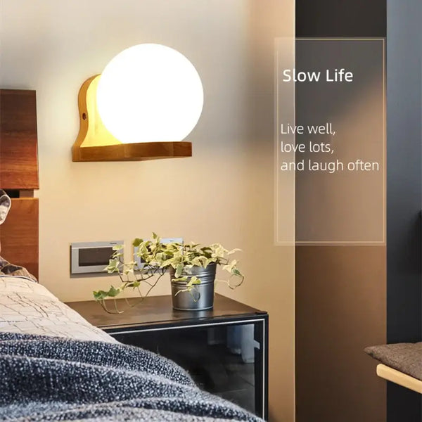 Wood and Frosted Glass Japanese Minimalist Sconces with glowing round light, enhancing a serene bedroom environment.