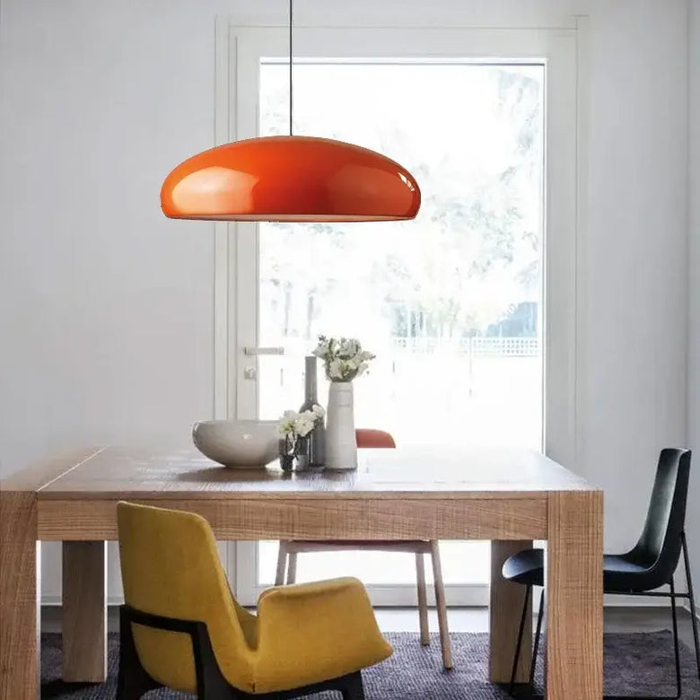 Simple Hanging Lamp in modern dining area with orange shade and wooden table.