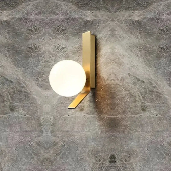 Contemporary Golden Wall Lamp with Glass Ball mounted on textured wall
