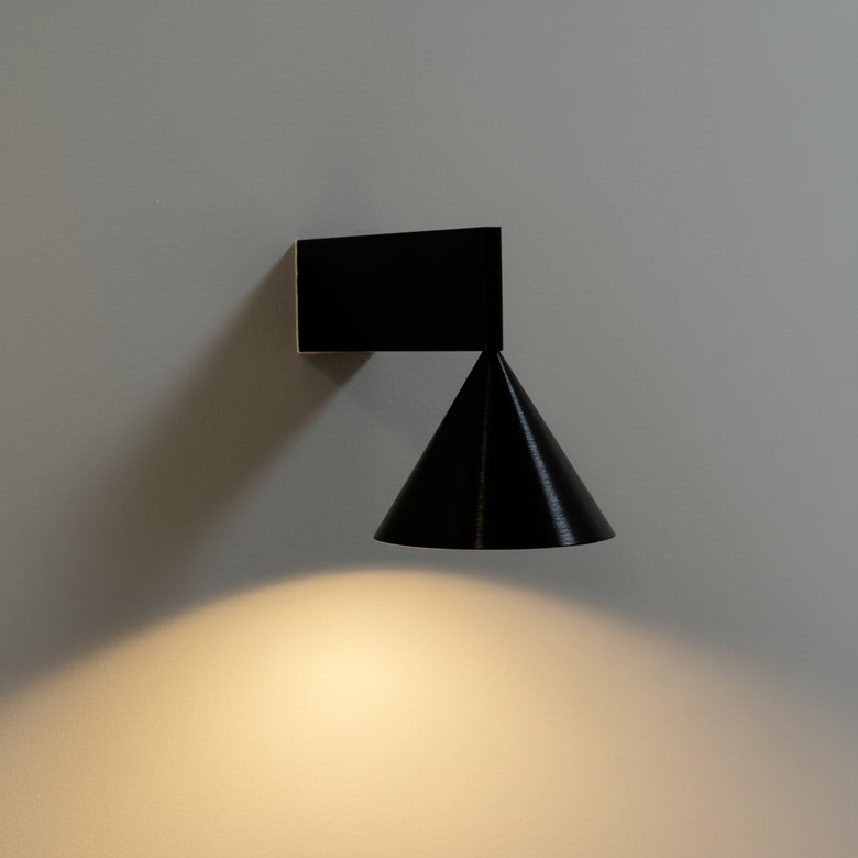Hero Black wall-mounted light fixture casting a warm glow on a gray wall.