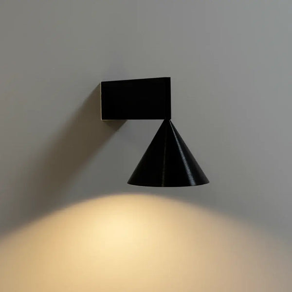 Hero Black wall-mounted light fixture casting a warm glow on a gray wall.