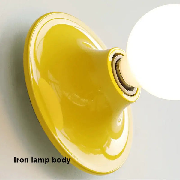 80s revival wall light showcasing a vibrant yellow UFO shape with an iron lamp body and glowing bulb.