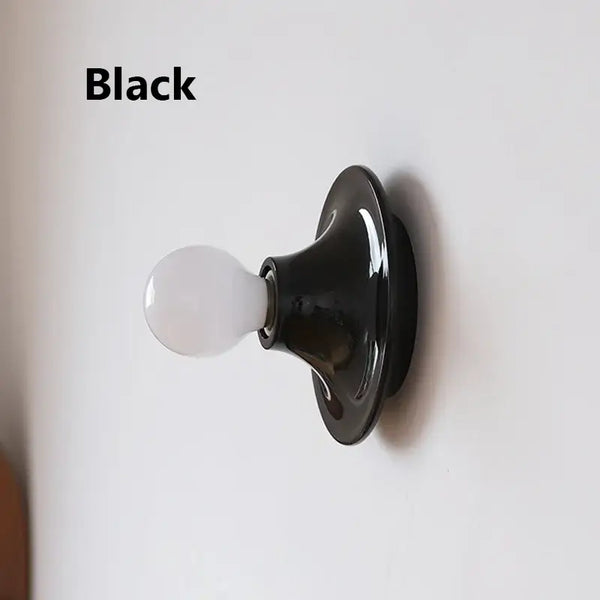 80s revival wall light in black with UFO shape and white bulb, perfect for retro decor.