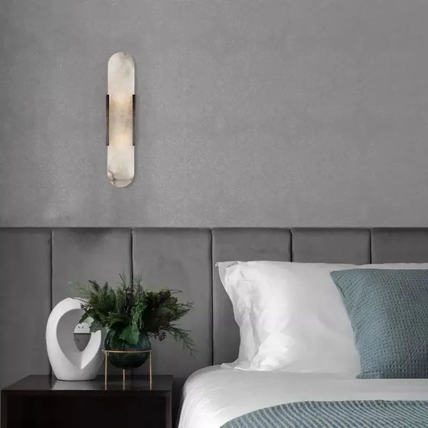 Posh Marble & Gold Roman Villa Sconce illuminating a modern bedroom wall.