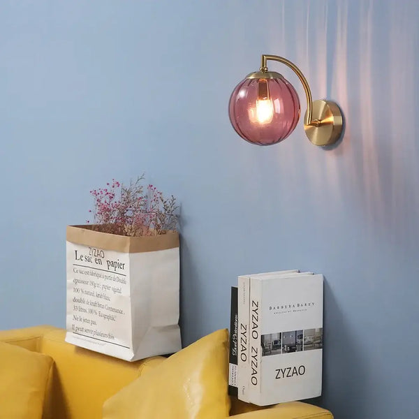Colourful Glass Modern Wall Light illuminating a blue wall beside a yellow couch and a stylish vase.
