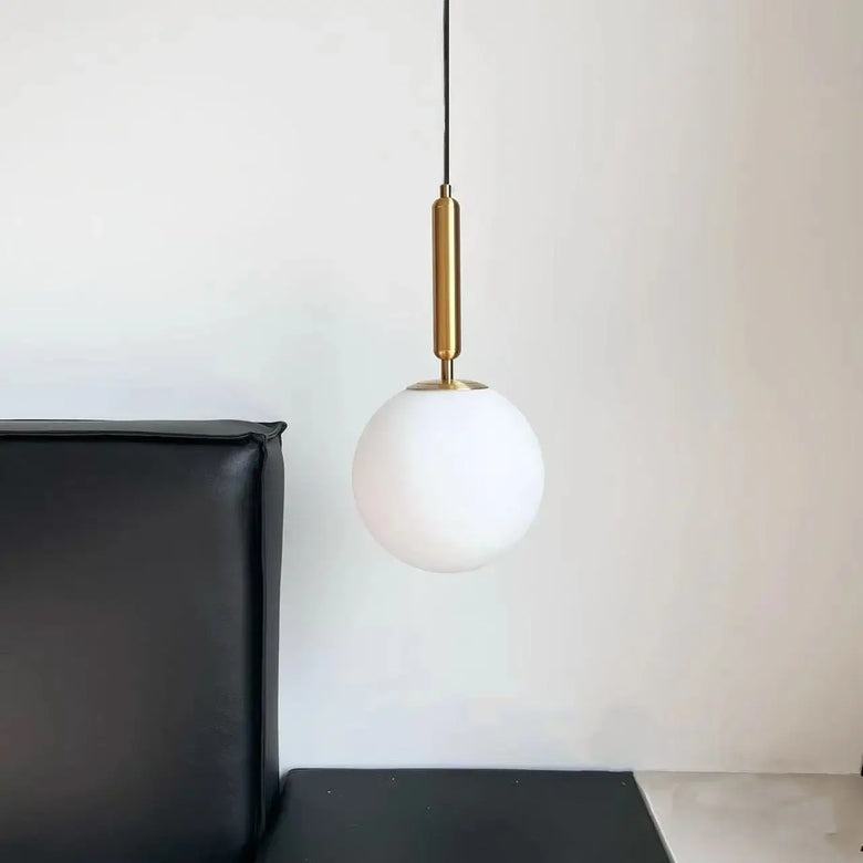Modern Gold Glass Ball Pendant hanging above a black sofa, adding elegance to contemporary interior decor.