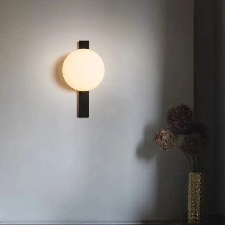 Decorative Lighting Fixture With Milk White Glass Sphere mounted on a wall, casting a warm glow in a stylish interior.