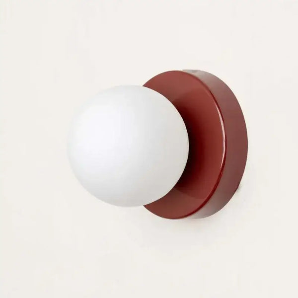 Colourful Macaron wall lamp with a red base and white globe, a playful and modern design for stylish interiors.