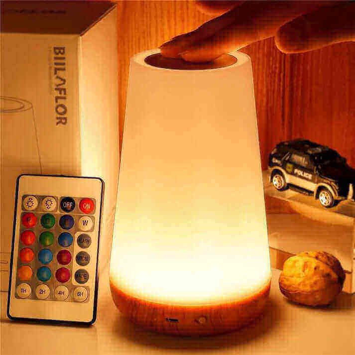 Auxmir Table Lamp glowing with remote control on wooden surface, enhancing room ambiance.