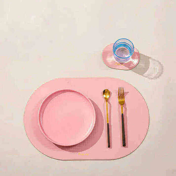 Modern dining setup with pink placemat featuring a plate, cutlery, and glass. Placemats or tablecloths?