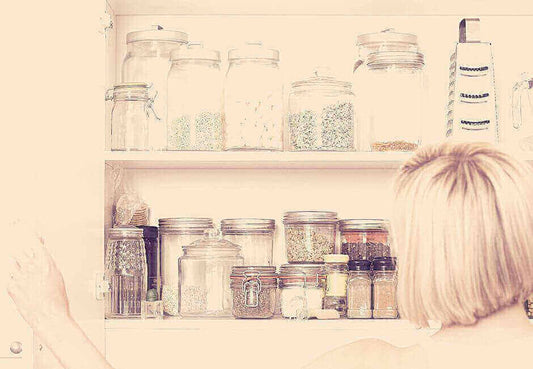 Why use Colorful Kitchen Canisters? Woman organizing glass jars and canisters in kitchen cabinet.