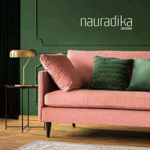 Pink sofa with green cushions against a dark green wall, illustrating the use of green in interior design by Nauradika London.