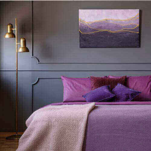Modern bedroom featuring purple decor showcasing the Use of Purple in Interior Design with purple pillows and wall art.
