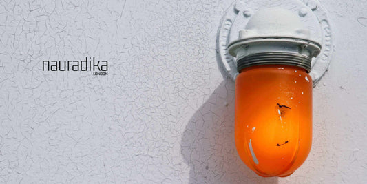 Industrial-Inspired Lighting Options with an orange wall-mounted light fixture on a white textured wall.