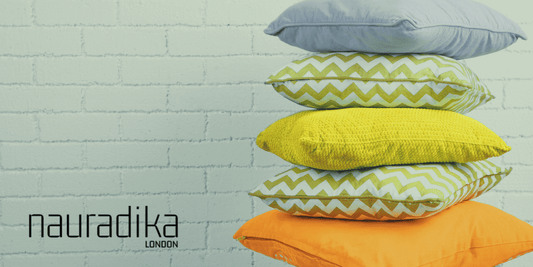 Colorful throw pillows stacked against a white brick wall, illustrating 10 Ways to Refresh Your Living Room on a Budget.
