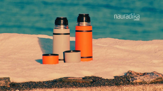 Are thermos bottles a good gift idea? Two thermos bottles on snowy ground with Nauradika branding in the background.