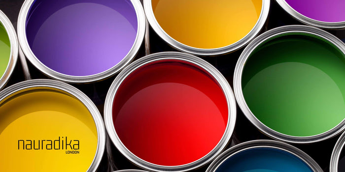 Open paint cans showcasing various colors, emphasizing 'Use accent colors sparingly in interior design' approach by Nauradika.