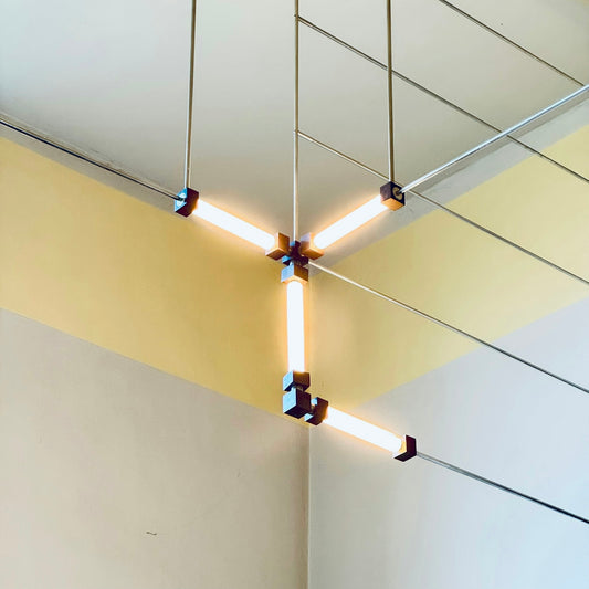 Modern y-shaped light fixture with glowing tubes.
