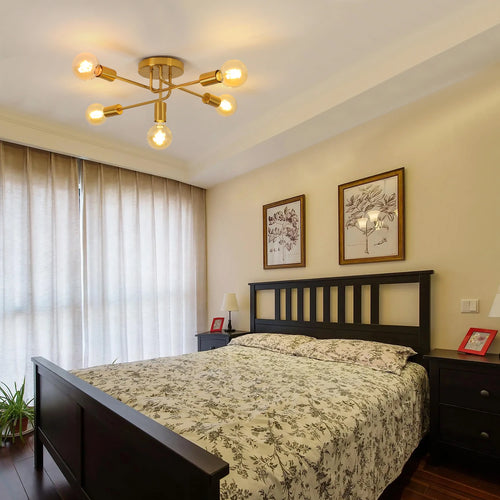 Modern Gold 5-Light Sputnik Ceiling Light with six glowing bulbs, installed in a bedroom above a dark wood bed with a floral-patterned duvet.