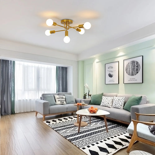 Modern living room featuring Gold 5-Light Sputnik Ceiling Light with glowing white globe bulbs, styled with a gray sectional sofa, black-and-white patterned rug, and light green walls.