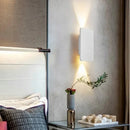 Brushed Gold/Black Double Head Wall Light illuminating a modern bedroom wall with stylish minimalism.